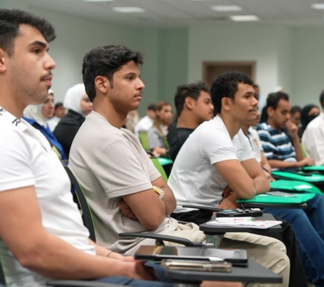 Students attending a lecture at Canadian College of Kuwait (CCK), engaged in learning with a lecturer presenting on a projector.